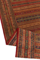 Detalle del reverso de la alfombra doblado hacia arriba, revelando la calidad artesanal del tejido y sus colores desde el dorso.