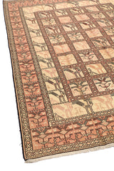 Esquina de la alfombra artesanal extendida, destacando su borde simétrico y motivos de aves enfrentadas