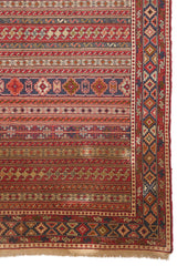 Detalle inferior derecho de la alfombra, mostrando motivos tribales en colores rojo, azul y beige.