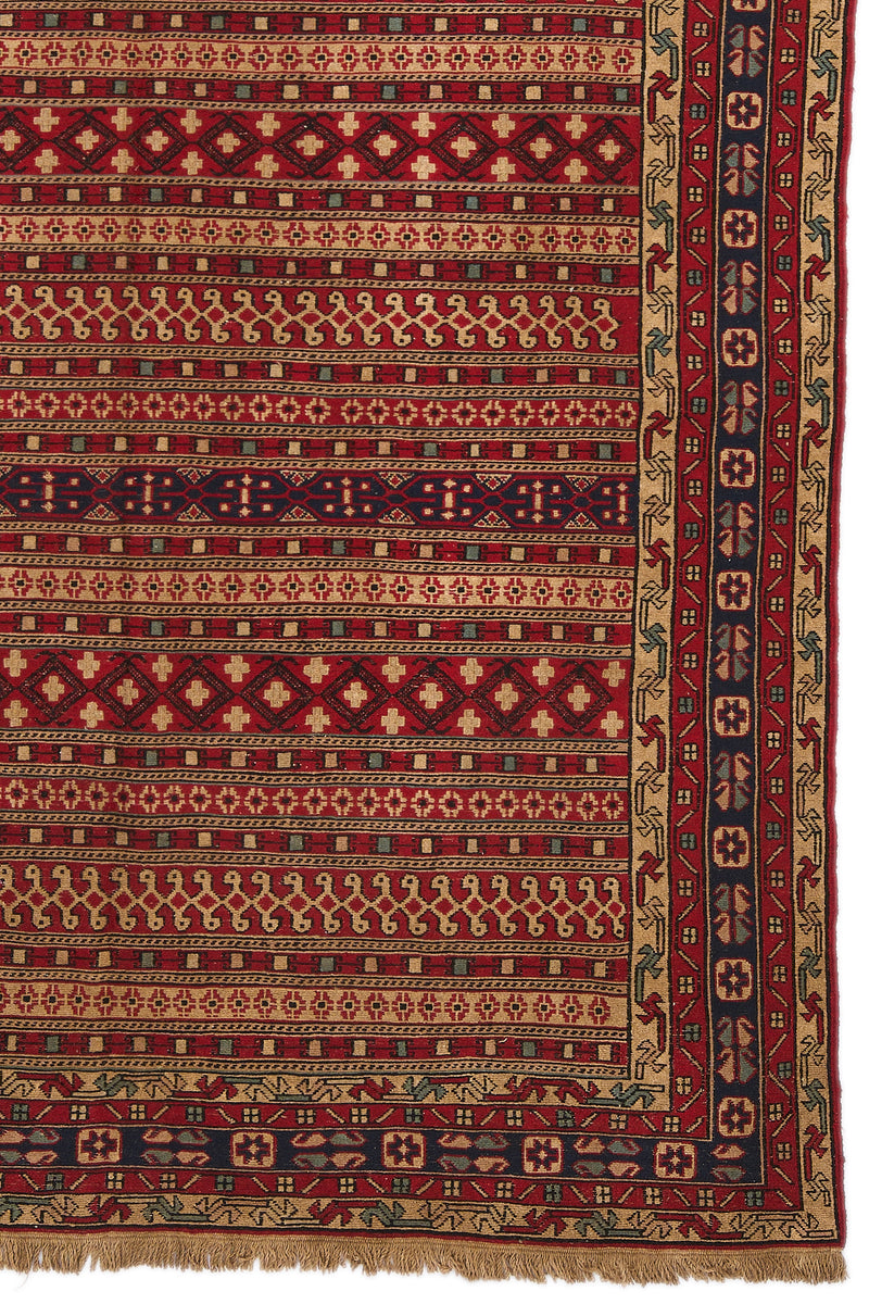 Detalle inferior derecho de la alfombra mostrando la guarda con flores estilizadas sobre fondo azul oscuro.