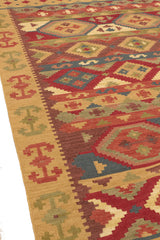 Vista en ángulo del lado izquierdo de la alfombra, resaltando sus figuras simétricas y combinación de colores cálidos.