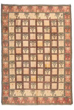 Vista frontal completa de una alfombra vintage con patrón cuadriculado y detalles tribales en tonos beige, rosado y dorado.
