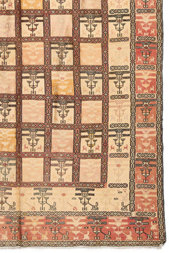 Detalle del extremo inferior derecho de la alfombra, mostrando los motivos geométricos y colores desgastados en beige y rosado.
