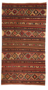 Alfombra kilim tradicional vista desde arriba, con franjas horizontales en tonos cálidos y motivos geométricos en forma de rombos.