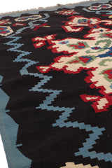 Vista lateral cercana de la alfombra que resalta el relieve y la textura del tejido sobre fondo negro con patrones en zigzag azul.