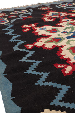 Vista lateral cercana de la alfombra que resalta el relieve y la textura del tejido sobre fondo negro con patrones en zigzag azul.