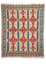 Alfombra artesanal vista completa, con fondo beige y motivos geométricos en rojo y azul