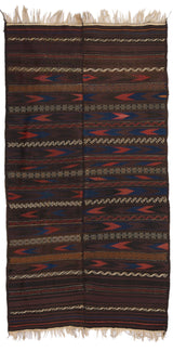 Alfombra tejida a mano con base oscura y patrones horizontales en rojo, azul y beige, con flecos en los bordes superiores.