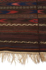Vista lateral de la alfombra destacando la textura del tejido y los patrones de zigzag en beige sobre fondo marrón.