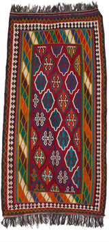 Vista completa de una alfombra artesanal con fondo rojo intenso, decorada con medallones geométricos y múltiples franjas coloridas en el borde.