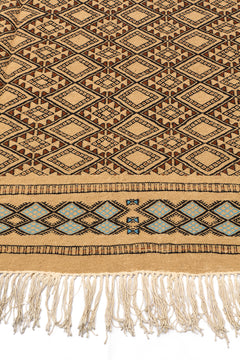 Vista angular de la alfombra mostrando los rombos en patrón repetitivo central y la guarda decorativa celeste.
