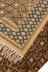 Detalle de la parte trasera de la alfombra doblada, mostrando el reverso del diseño artesanal y los flecos de lana.