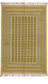Vista completa de una alfombra artesanal con base amarillo-mostaza y patrones geométricos negros y beige, enmarcada con flecos en los extremos.