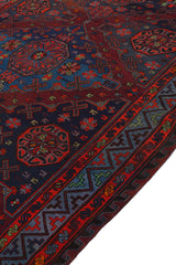 Plano diagonal de la alfombra kilim resaltando patrones entrelazados en rojo, azul y verde sobre fondo oscuro.