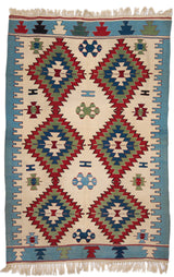 Vista completa de una alfombra kilim de fondo beige con grandes motivos geométricos en forma de diamante, en tonos rojo, verde y azul.