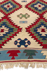 Perspectiva angular que resalta los colores vivos y la simetría de los rombos escalonados en el centro de la alfombra.
