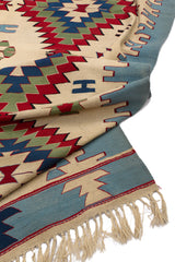 Vista del reverso de la alfombra kilim, mostrando la textura del tejido y los flecos, con los colores visibles al reverso del patrón.