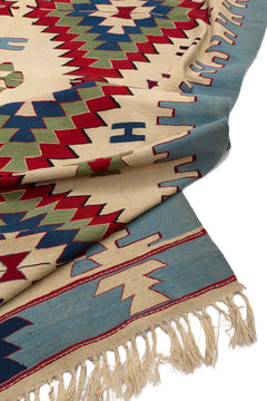 Vista del reverso de la alfombra kilim, mostrando la textura del tejido y los flecos, con los colores visibles al reverso del patrón.