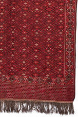 Detalle del extremo inferior derecho de la alfombra roja, mostrando el borde decorativo y los patrones romboidales en primer plano.