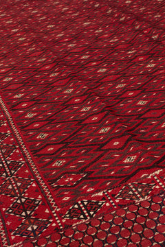 Vista en ángulo bajo de la alfombra kilim roja, enfocando el diseño en zigzag y la simetría de los rombos alineados.