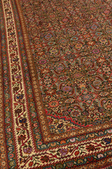 Perspectiva lateral de alfombra que resalta el patrón simétrico de flores sobre fondo verde oscuro y guarda marfil decorada.