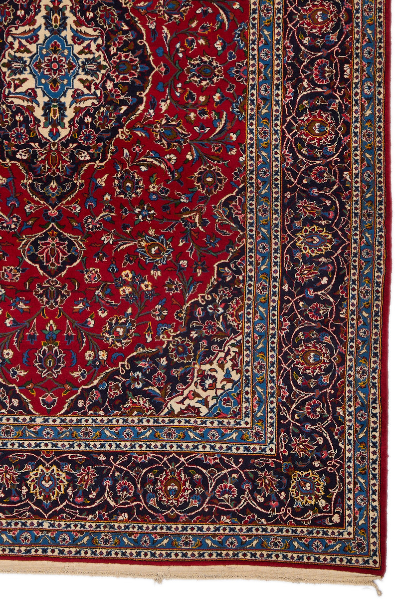 Detalle inferior derecho de la alfombra, mostrando el borde azul celeste con flores estilizadas y arabescos en tonos marfil y rojo oscuro.