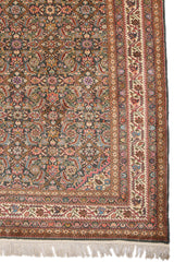 Detalle inferior derecho de la alfombra persa mostrando una compleja repetición de flores estilizadas en tonos rosa, morado y beige, con una guarda marfil adornada con flores rojas y azul celeste.