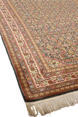 Detalle superior izquierdo de la alfombra persa donde se aprecian mejor las guardas internas en color ladrillo con diseño floral repetitivo y el contraste con la guarda externa marfil.
