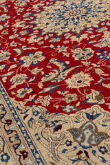 Primer plano del diseño central en forma de estrella floral beige con detalles en azul sobre fondo rojo, con flores estilizadas alrededor.