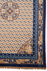 Detalle del medallón central azul y beige de la alfombra persa, rodeado por patrones geométricos estrellados sobre fondo beige.