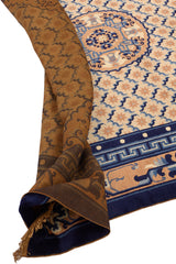 Detalle de la alfombra persa doblada, revelando el reverso de color marrón y los patrones tradicionales en tonos azules y beige
