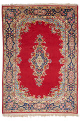 Alfombra persa con fondo rojo intenso y medallón central floral en tonos azul marino, verde y rosa, rodeado por un marco floral decorativo en colores celeste, beige y azul marino.