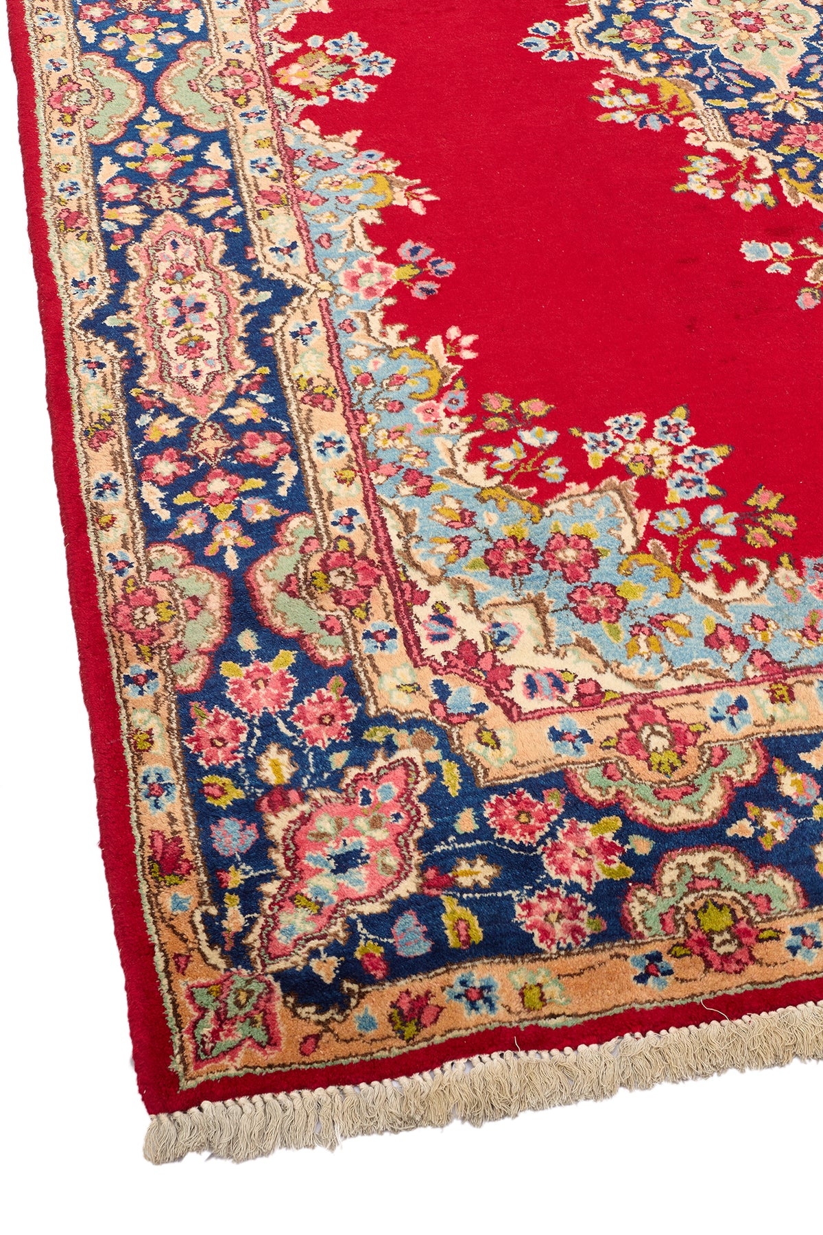 Esquina inferior derecha de la alfombra persa, destacando la riqueza de colores y los detalles florales del marco decorativo sobre fondo azul y beige.