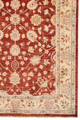 Detalle del borde inferior derecho que muestra el patrón floral y la transición entre los colores principales de la alfombra.