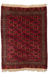 Vista completa de alfombra con fondo rojo oscuro y patrón repetitivo de motivos geométricos.
