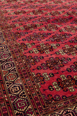 Perspectiva lateral de la alfombra enfocando el contraste entre el borde decorativo y el campo rojo principal.