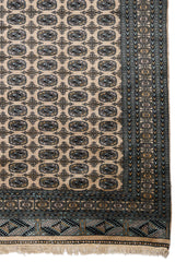 Detalle lateral de la alfombra mostrando motivos geométricos en negro y dorado.