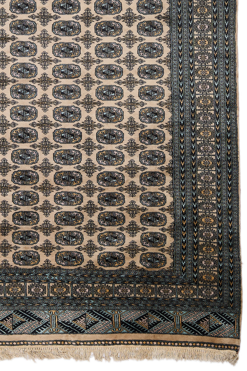 Detalle lateral de la alfombra mostrando motivos geométricos en negro y dorado.