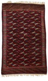 Vista completa de alfombra tradicional turcomana con fondo marrón oscuro y motivos geométricos repetitivos en tonos rojo, beige y azul.