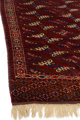 Perspectiva angular de la alfombra destacando los patrones tribales en zigzag rojo y azul y el borde decorado con motivos étnicos.