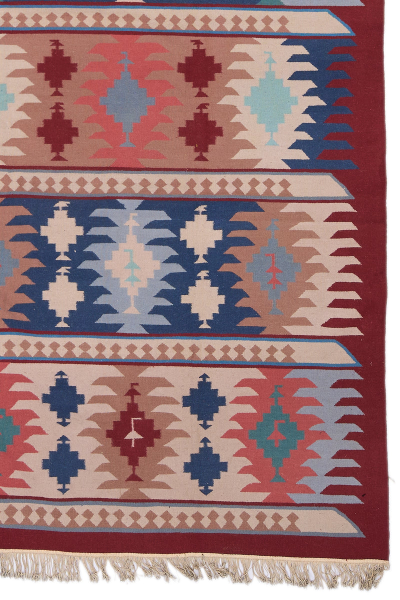 Detalle inferior derecho de la alfombra kilim mostrando los flecos, las franjas y los patrones repetitivos de inspiración tribal.