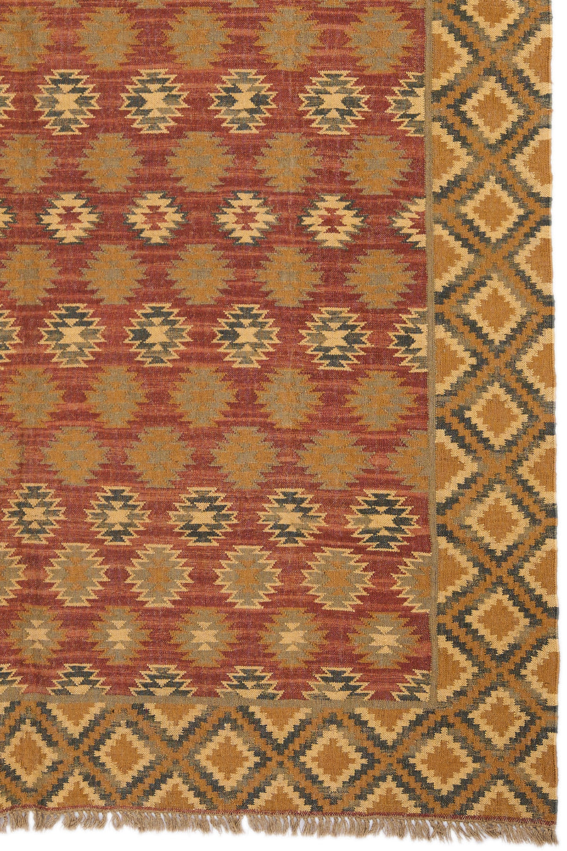 Detalle del borde derecho de la alfombra kilim mostrando el contraste entre el centro rojo con figuras doradas y la guarda de rombos en tonos cálidos.