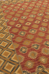 Perspectiva diagonal de la alfombra kilim mostrando la repetición armoniosa de motivos centrales y el marco geométrico exterior.