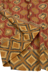 Detalle de la esquina doblada de la alfombra kilim, mostrando el reverso del tejido y los flecos artesanales.