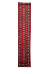 Vista completa de alfombra tipo corredor con fondo rojo vivo y motivos repetitivos en forma de medallón beige, negro y verde