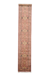 Vista completa de alfombra tipo corredor en tonos salmón, crema y negro, con diseño central simétrico de inspiración floral y bordes detallados
