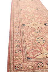 Perspectiva en ángulo de alfombra tipo corredor destacando el diseño floral simétrico sobre fondo rosado claro y bordes ornamentales con flores