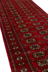 Vista en ángulo mostrando la textura y los bordes decorativos de la alfombra oriental.