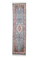 Vista completa de alfombra persa de pasillo en tonos celestes con diseño floral simétrico y medallón central beige.