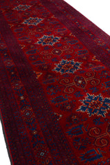 Vista en ángulo de la alfombra Kazak mostrando la profundidad del color rojo y la precisión de los patrones geométricos.